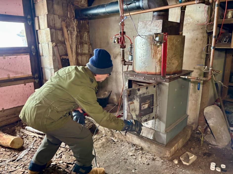A man looks into a ba<em></em>sement furnace.