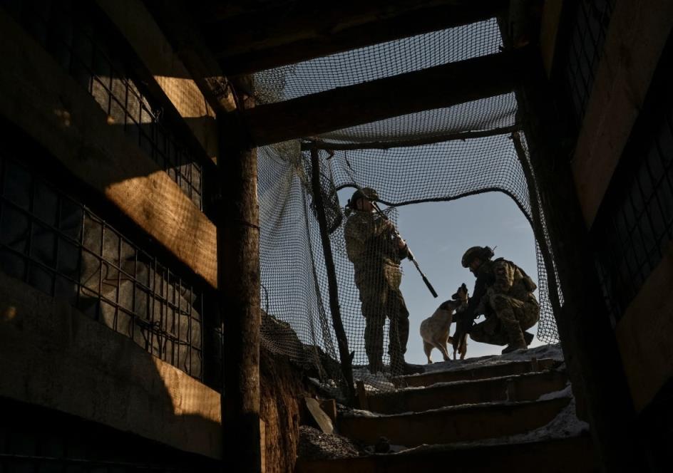 Two Ukrainian soldiers stand alo<em></em>ngside a dog in Ukraine's Zaporizhzhia region.