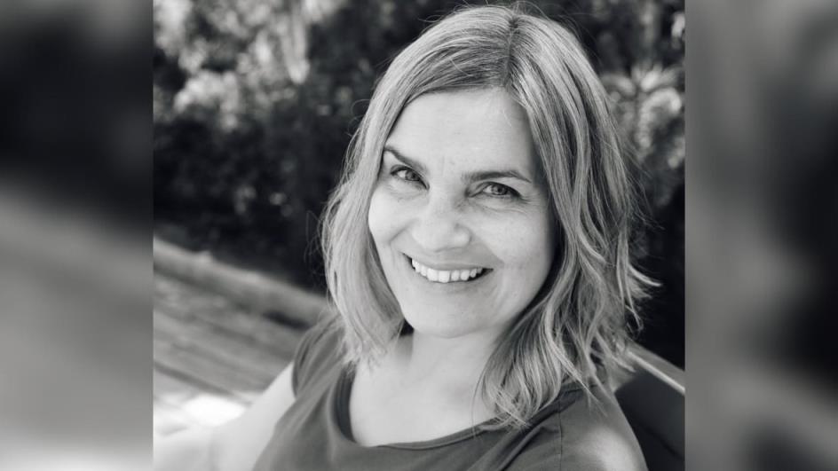 A black-and-white headshot of a person with medium-length hair, who is smiling.
